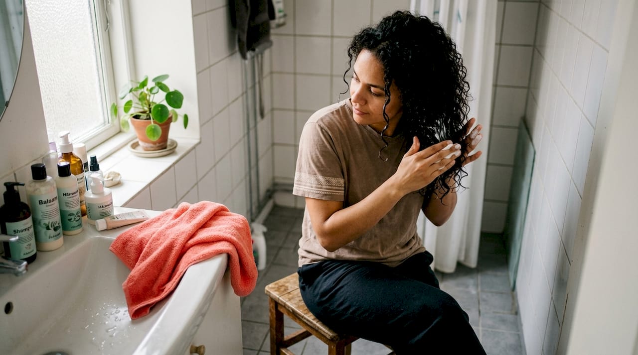 En kvinde forkæler sine krøller med en dybdevirkende hårkur