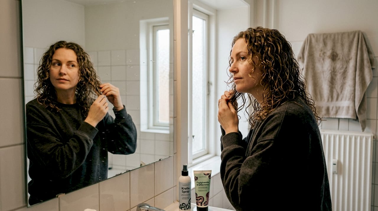 En kvinde står foran spejlet og tjekker sine krøller