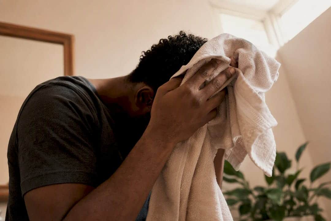 Mand tørrer kort, krøllet hår med mikrofiberhåndklæde